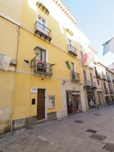 un edificio amarillo con balcones en una calle en b&b del corso, en Iglesias