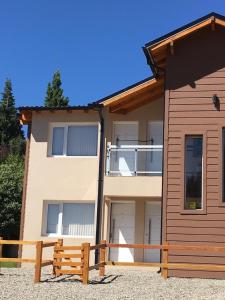 dom z drewnianym płotem przed nim w obiekcie Apartamento El Maiten w mieście Bariloche
