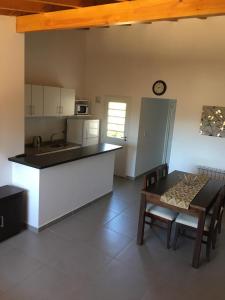 eine Küche mit einer Theke, einem Tisch, einem Tisch und Stühlen in der Unterkunft Apartamento El Maiten in San Carlos de Bariloche