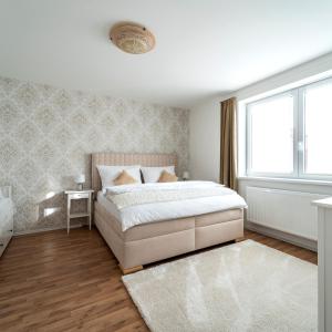 a white bedroom with a large bed and a window at HOME 223 - designový apartmán in Jihlava