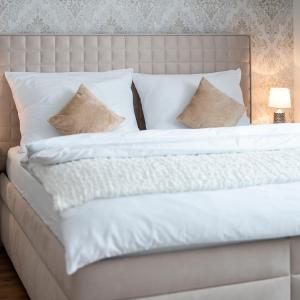 1 cama grande con sábanas y almohadas blancas en HOME 223 - designový apartmán, en Jihlava