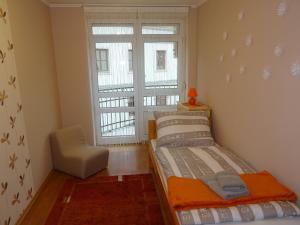 a bedroom with a bed and a chair and a window at Teleki Apartman Kaposvár in Kaposvár