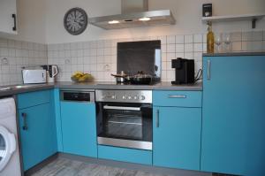 a kitchen with blue appliances and a clock on the wall at Möllenbecks Messewohnungen in Ratingen