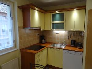 cocina con armarios amarillos, fregadero y ventana en Teleki Apartman Kaposvár, en Kaposvár