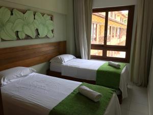a hotel room with two beds and a window at Enseada Praia do Forte in Praia do Forte +116 photos