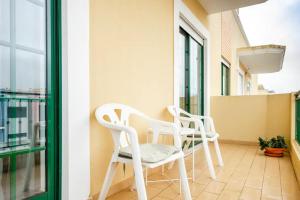 two white chairs sitting on a balcony at Apartamento Parque Ria Formosa, Olhão in Olhão