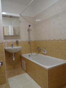 a bathroom with a bath tub and a sink at Teleki Apartman Kaposvár in Kaposvár