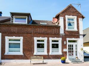 a brick house with white windows and a bench at Ferienwohnung am Dorfteich in Fehmarn