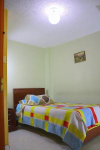 a bedroom with a bed with a colorful blanket at Hostel Casa Alb in Bogotá