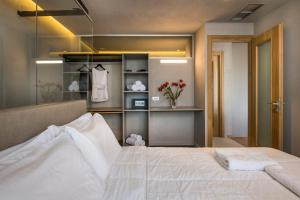 Icarus Hotel في كالاماكي: غرفة نوم بسرير ابيض وخزانة