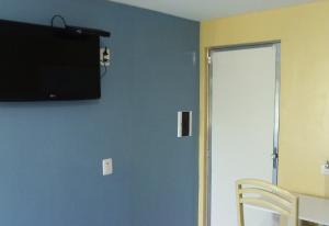 a room with a blue wall with a television on the wall at Pousada NS Fátima in Fortaleza