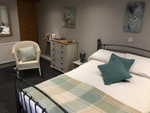 a bedroom with a bed and a chair and a dresser at Linden Tree Holiday Apartments in Thirsk