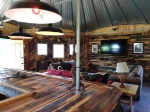 a living room with a wooden table and a tv at The Highlander - Rustic Mountain Yurt in Genoa