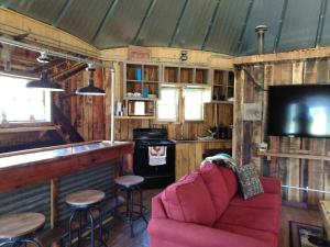 uma sala de estar com um sofá vermelho e um bar em The Mountaineer - Rustic Mountain Yurt em Genoa