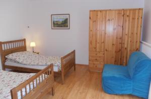 1 dormitorio con 2 camas y silla azul en Sváb Ház, en Veszprémfajsz