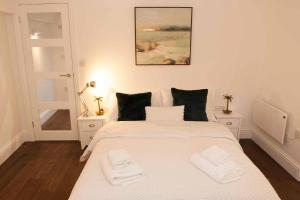 a bedroom with a white bed with two white towels on it at Silver View-Spa Hot Tub-Beautiful Sea Views-Free Parking- Central Lyme Regis in Lyme Regis