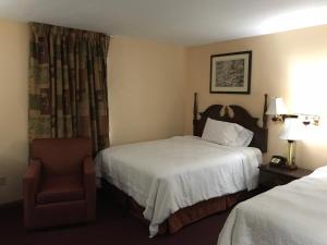 una habitación de hotel con 2 camas y una silla en Motel Town House, en Bedford