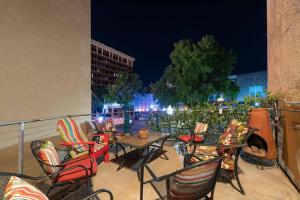 un patio con mesas y sillas en el balcón por la noche en Green Door Lofts -Magnolia Loft, Silos/Downtown en Waco