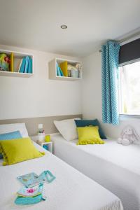 2 Betten in einem Zimmer mit gelben und blauen Vorhängen in der Unterkunft Le Goh Velin in Saint-Gildas-de-Rhuys