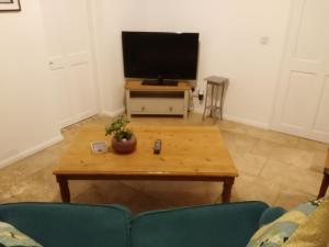 ein Wohnzimmer mit einem Couchtisch und einem TV in der Unterkunft Garden Cottage in Sleaford