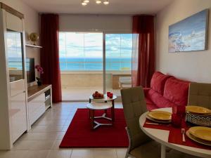 a living room with a red couch and a table at Apartamentos Apolo 16 in Calpe