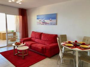a living room with a red couch and a table at Apartamentos Apolo 16 in Calpe