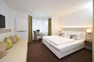 a bedroom with a large white bed and a desk at Hotel Bayerischer Hof in Lindenberg im Allgäu