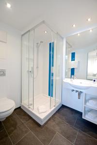 a bathroom with a shower and a toilet and a sink at Hotel Bayerischer Hof in Lindenberg im Allgäu