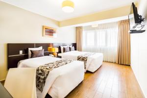 a hotel room with two beds and a window at Hotel El Tambo 2 in Lima