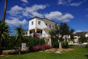 une maison blanche avec une cour avec des arbres et des buissons dans l'établissement One-Bedroom Apartment in Vinisce I, à Vinišće
