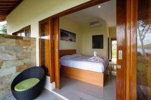 a small bedroom with a bed and a chair at Tunak Cottage in Bumbang