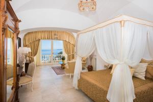 a bedroom with a canopy bed with a chandelier at Hotel Villa Gabrisa in Positano