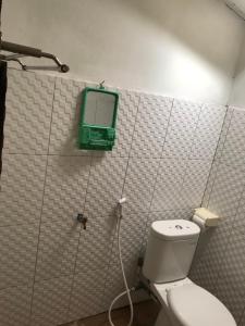 a bathroom with a toilet and a green box on the wall at Ova Baluk Bungalow in Nembrala