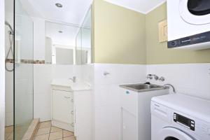 a bathroom with a sink and a washing machine at Levuka Unit 4 14 Moreton Pde Kings Beach in Caloundra