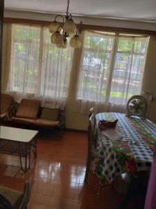 a living room with a table and a couch and windows at Maison Au pied du Volcan in Curepipe