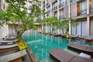 een zwembad in een gebouw met bomen en stoelen bij Hotel Terrace at Kuta in Legian