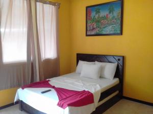 a bedroom with a white bed with a painting on the wall at Cabinas Hukats Secret Jungle in Puerto Viejo