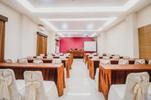 una sala de conferencias con mesas, sillas y una pantalla en RedDoorz Plus near Universitas Negeri Makassar, en Makassar