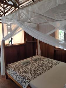 a bedroom with a bed with a mosquito net at Harmony Bay Resort and Dive Center in Wakai
