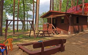 a log cabin with a playground in front of it at Domek Fiona in Boszkowo +4 photos