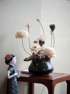 a black vase with flowers in it on a table at SHANGHAI-DECO Hotel-Free shuttle bus from Pudong Airport and Disneylan in Shanghai