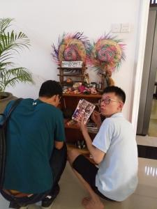 Dois homens sentados à mesa a ler um livro. em Cosy Nest Home stay em Negombo