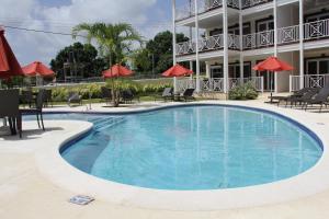 a swimming pool in front of a hotel with red umbrellas at Lantana Resort Barbados by Island Villas in Saint James