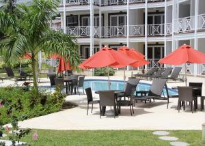 an outdoor patio with tables and chairs and umbrellas at Lantana Resort Barbados by Island Villas in Saint James