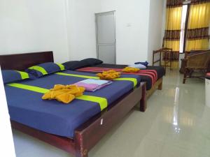 two beds in a room with yellow and blue at Selahn Inn in Katunayaka