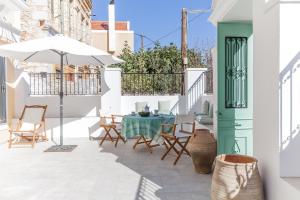 eine Terrasse mit einem Tisch, Stühlen und einem Sonnenschirm in der Unterkunft Casa Rinio in Symi