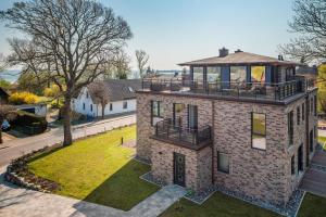 a brick house with a balcony on top of it at Villa Lotsenhäuser Rügen - Luxus Ferienhaus - 3 Schlafzimmer - Sauna - Dachterrasse mit Boddenblick in Breege