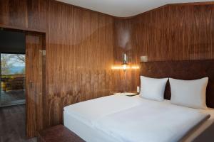 a bedroom with a white bed with a wooden wall at Villa Lotsenhäuser Rügen - Luxus Ferienhaus - 3 Schlafzimmer - Sauna - Dachterrasse mit Boddenblick in Breege