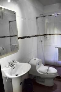 a white bathroom with a sink and a toilet at Hotel Sophia Real in Yopal