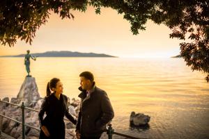 a man and a woman standing next to a body of water at Hotel Bellevue - Liburnia in Opatija
